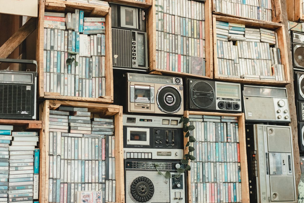 A nostalgic display of vintage cassette tapes and radios arranged on wooden shelves.