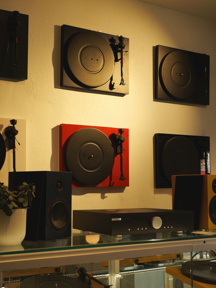 A music store display featuring turntables and speakers on shelves, showcasing modern audio equipment.